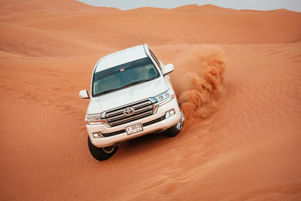 Dubai Desert Safari Price Guide A Toyota Land Cruiser navigating a challenging desert dune, showcasing off-road capabilities.