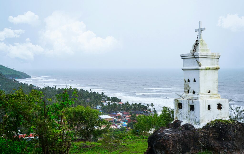 Hidden Beaches in Goa You Must Visit in 2026 View of the Anjuna coast with a white monument in the foreground, capturing the beauty of Goa's seaside.